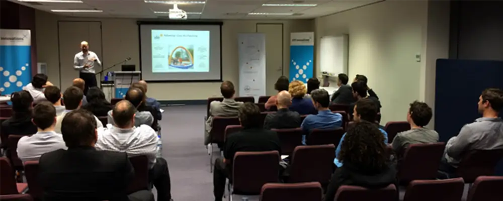 room full of people sitting listening to a speaker with a projector