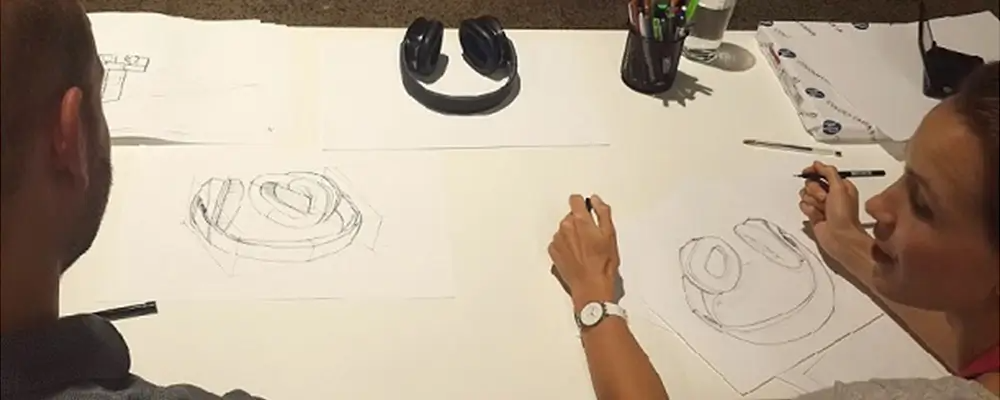 two people talking while sketching a pair of headphones