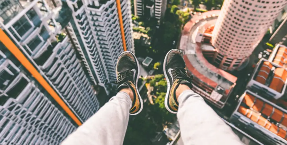 legs with feet in nike shoes handing off the side of a tall building