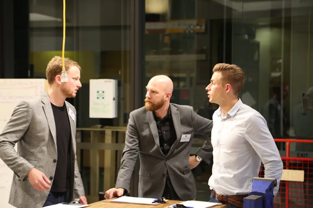 3 men in discussion in formal wear at SOMI hackathon