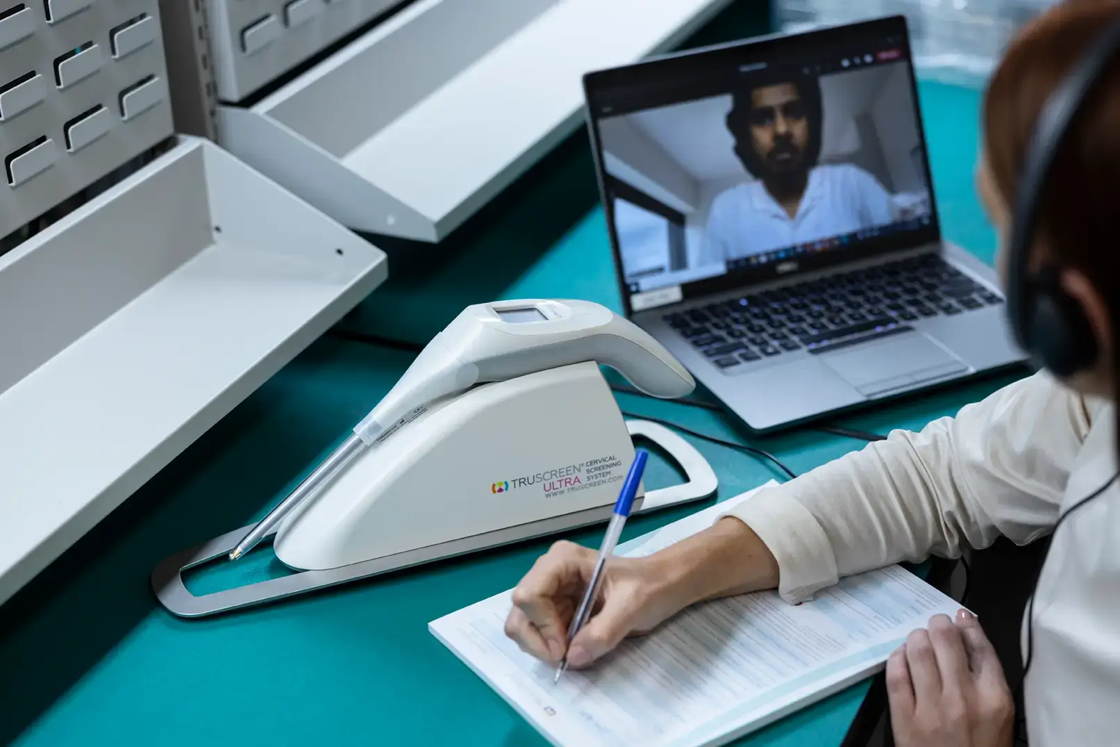 Woman writes note next to truscreen device while in online meeting on computer