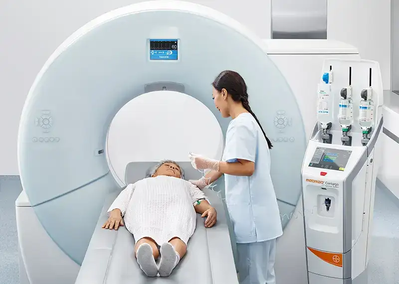 Clinician communicates to woman as she prepares her for CT scan, Medran centargo to the right